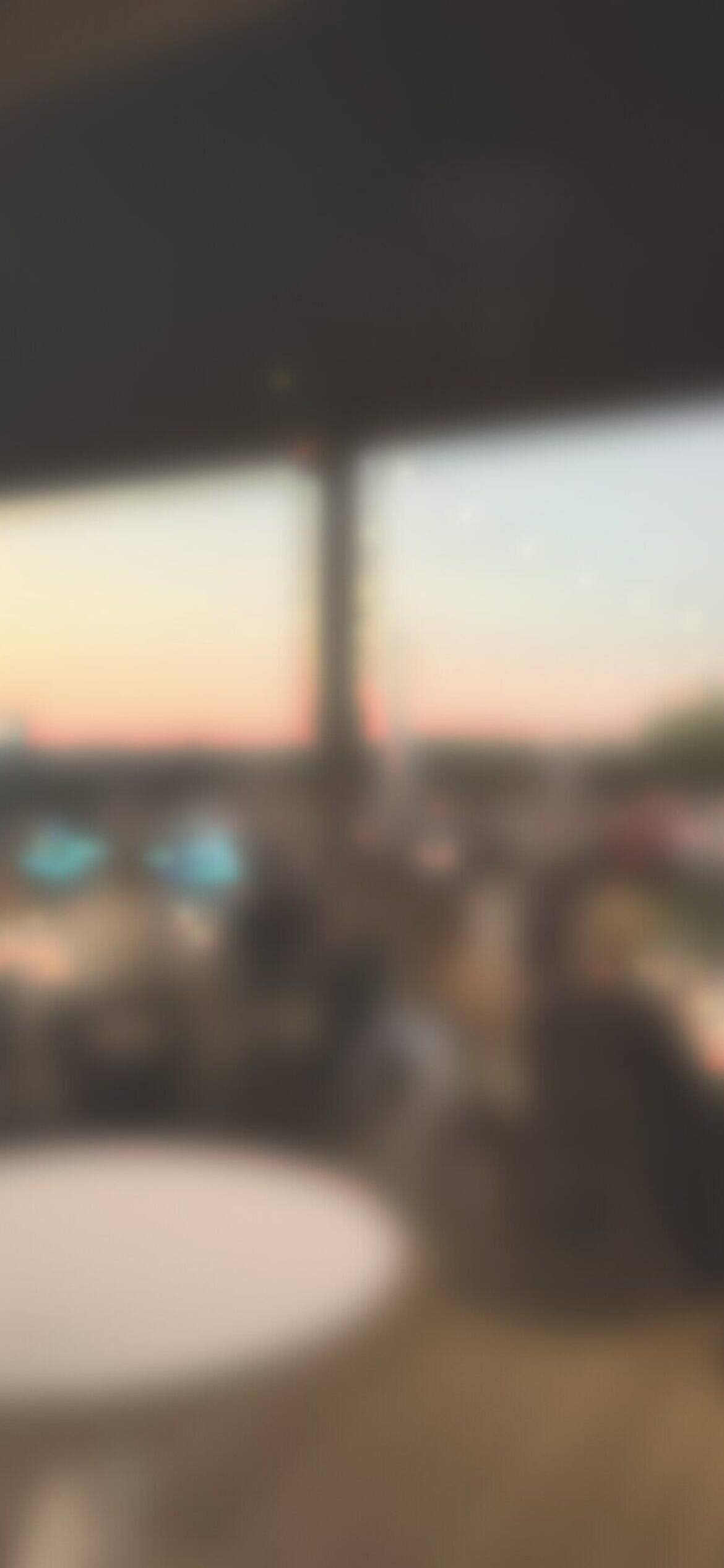 Guests at dinner on a covered deck at dusk, softly blurred
