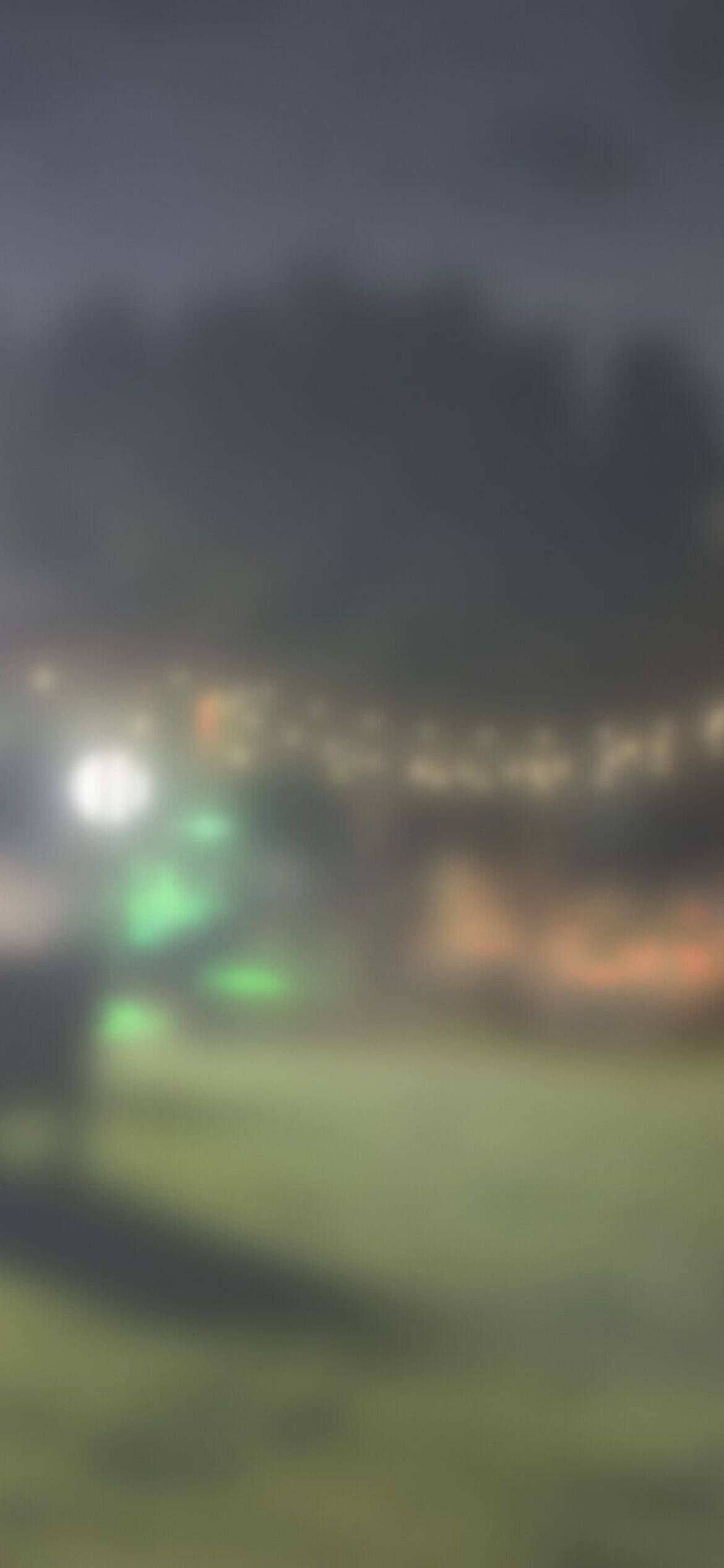 The same lawn after dark, every table full under string lights, softly blurred